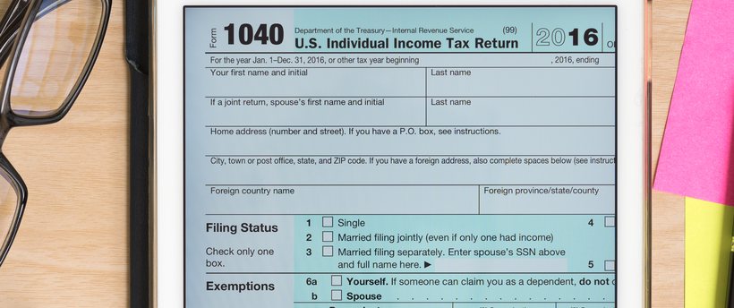 IRS Form 1040 on a tablet with a calculator and notes