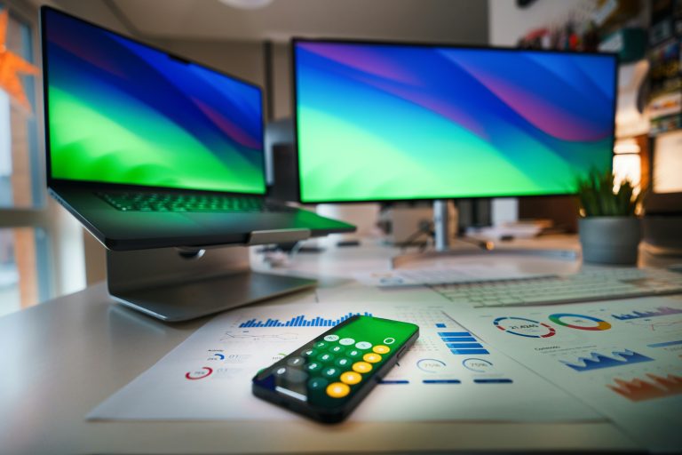 This image contains two computer screens, tax documents, and a mobile with calculator
